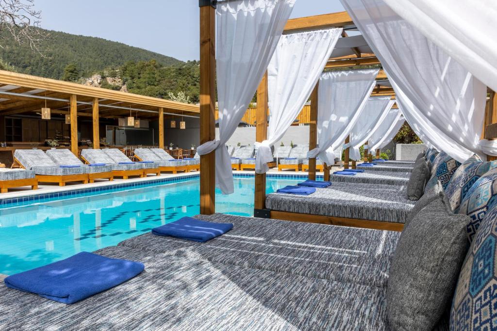 a row of beds next to a swimming pool at Skiathos Thalassa, Philian Hotels and Resorts in Skiathos