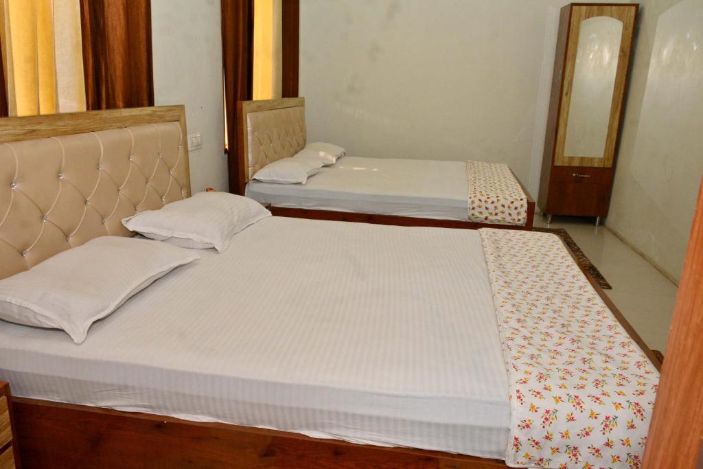Duas camas individuais num quarto com um espelho. em Corridor inn em Derā Nānak