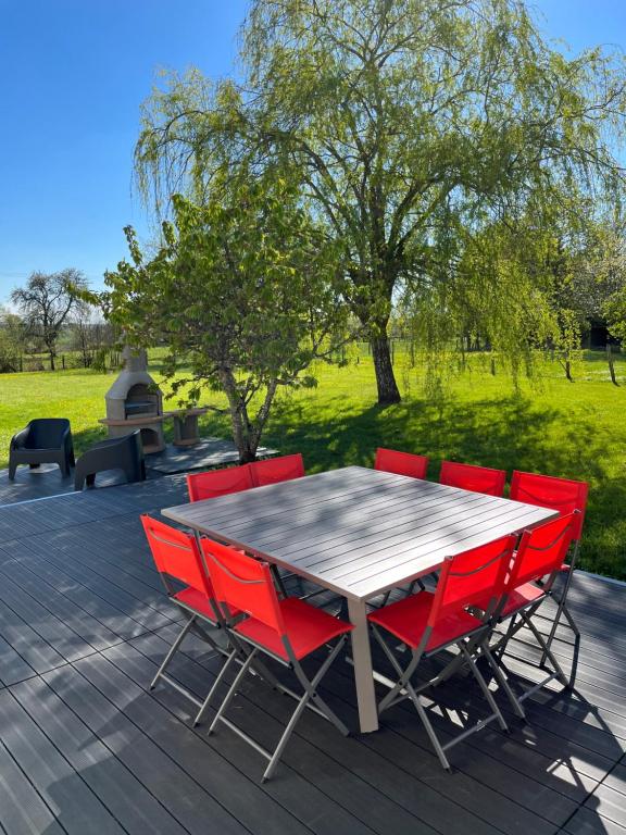 una mesa de madera con sillas rojas en una terraza en Gîte à l’orée du pré en Villiers-Saint-Benoît