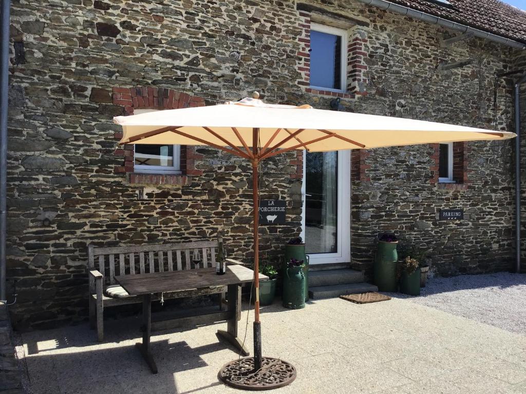 an umbrella and a bench in front of a building at La Porcherie at La Grande Houssaye in Villiers-Fossard