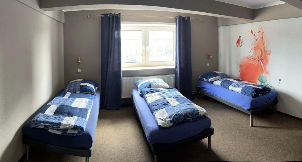 three beds in a room with a window at Hostel Fehmarn Mehrbett-Zimmer in Fehmarn