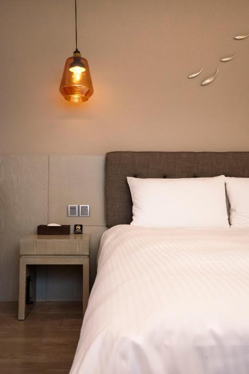 a bedroom with a bed and a nightstand with a white bed at Hub Hotel Kaohsiung Yawan Branch in Kaohsiung