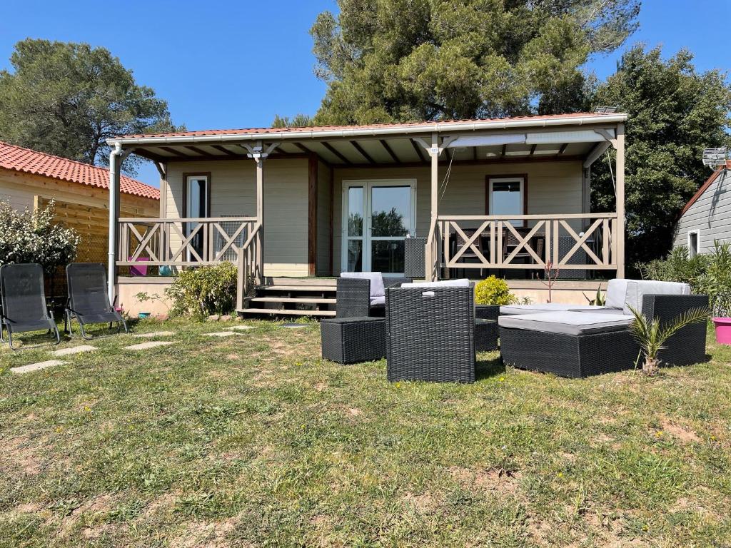 une maison avec une terrasse couverte et des chaises dans la cour dans l'établissement Châlet dans parc de loisirs 5 étoiles, à Puget-sur Argens