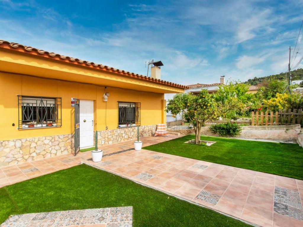 a yellow house with a yard with a courtyard at VILLA BLANCA 10 minutos de la Playa Costa brava in Maçanet de la Selva