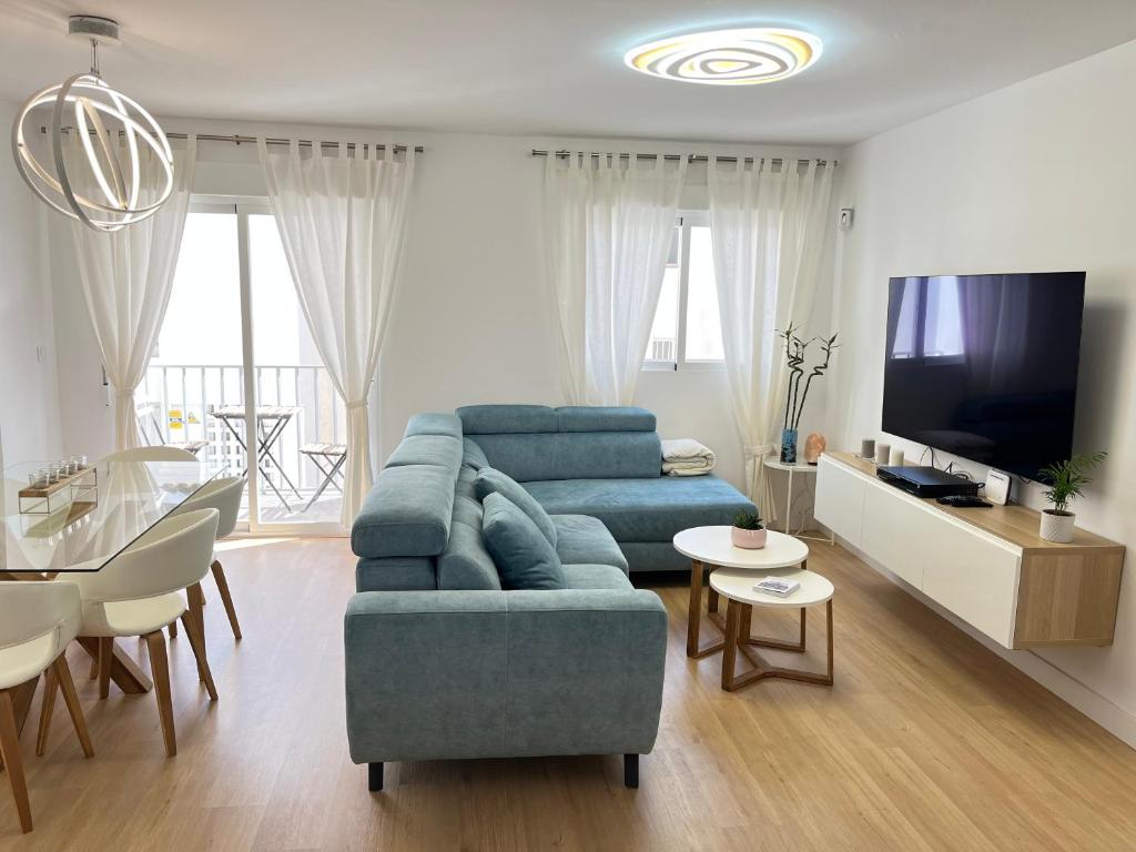 a living room with a blue couch and a tv at Casa del olivo in Almuñécar