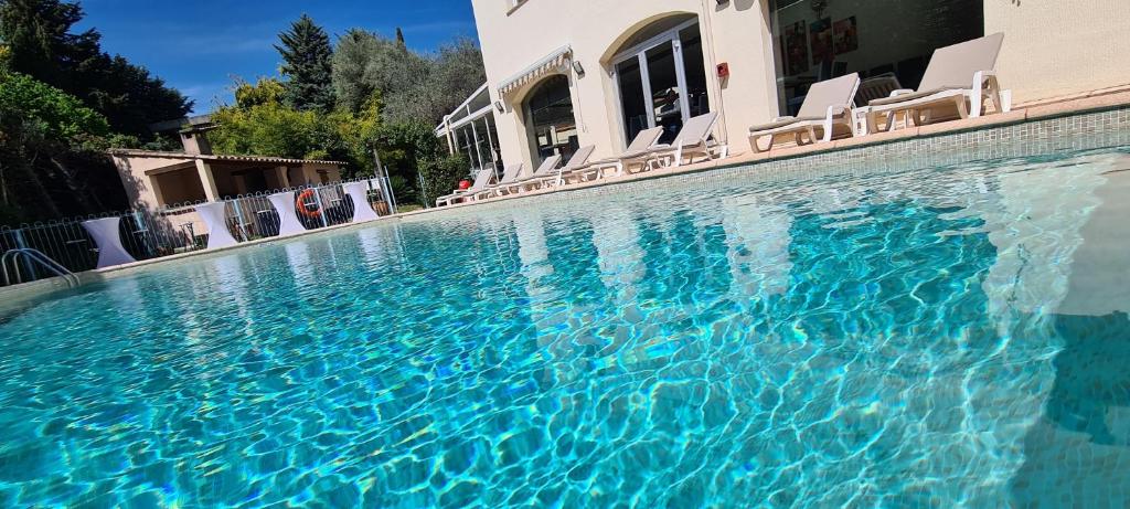 a swimming pool with blue water in front of a house at Le Floréal in Vence