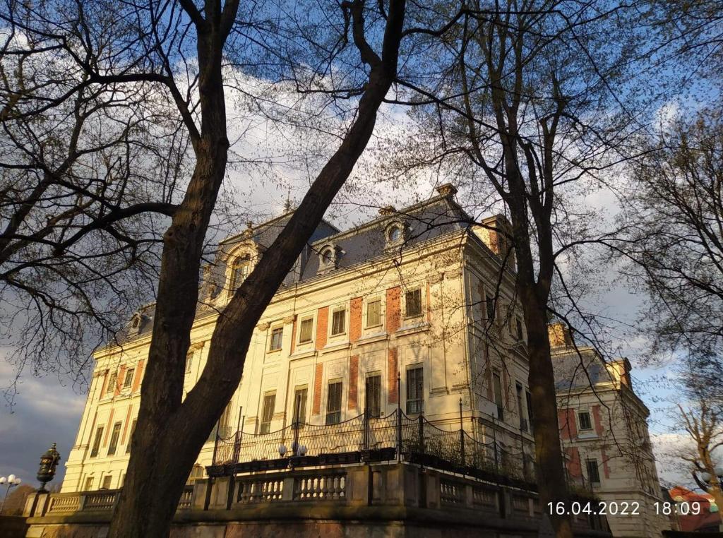 een groot wit gebouw met bomen ervoor bij Apartament przy Zamku in Pszczyna