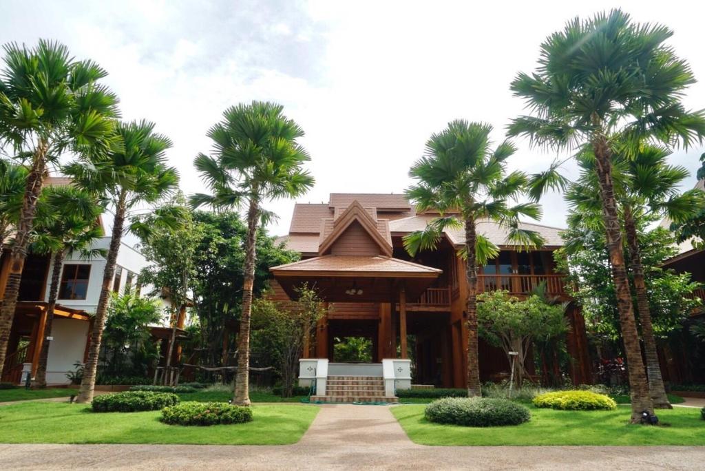 una casa con palmeras delante en Vanasin Residence, en Tak