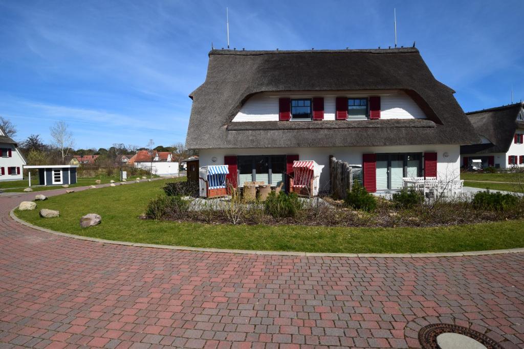 a house with a gambrel roof on a brick driveway at Dat Smucke Huus - strandnah unter Reet in Boltenhagen