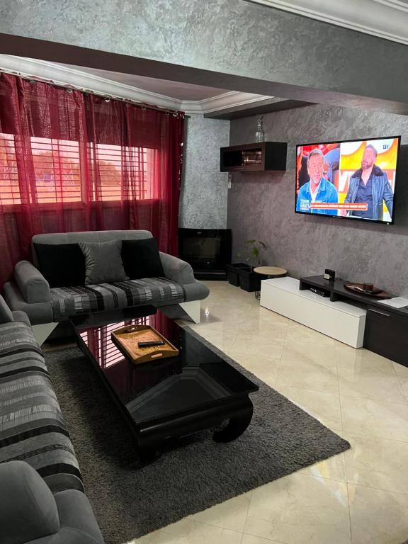 uma sala de estar com um sofá e uma televisão de ecrã plano em Duplex haut standing à 5min de la plage2 em Agadir