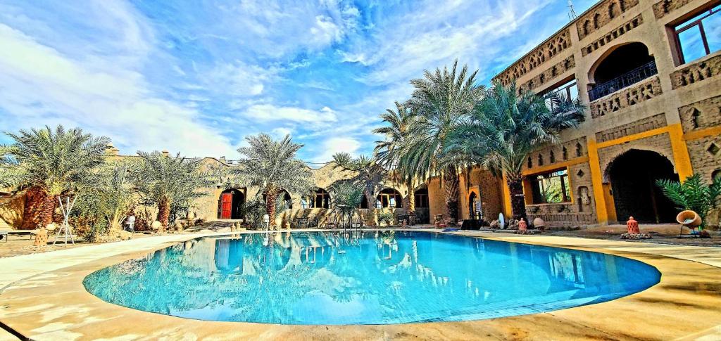 a swimming pool in the middle of a building with palm trees at AUBERGE KSAR MERZOUGA in Merzouga