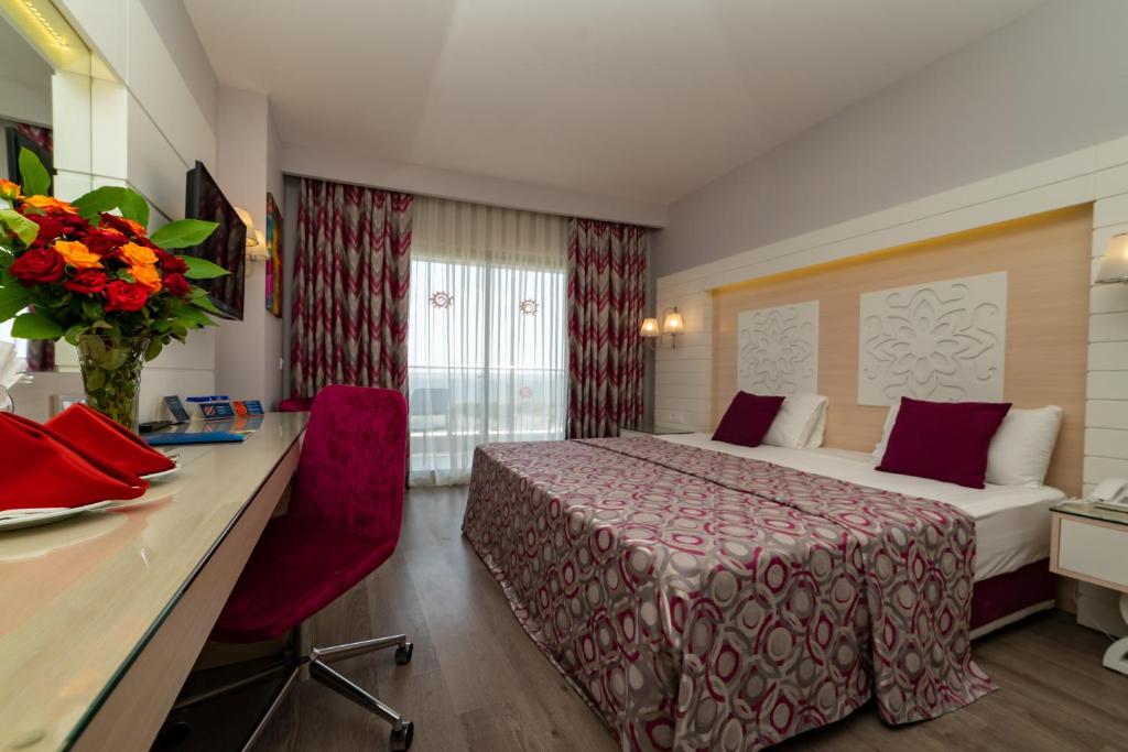 キジラガックにあるSunmelia Beach Resort Hotel & Spa-All Inclusiveのベッドとデスクが備わるホテルルームです。