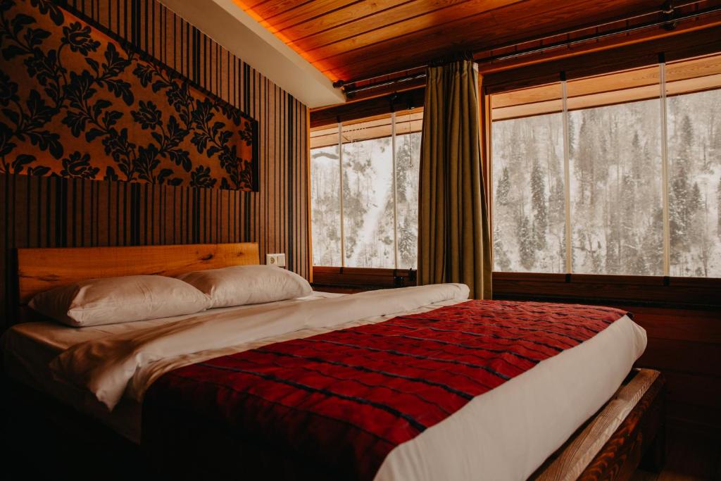 a bedroom with a large bed and two windows at Ayder Resort Hotel in Ayder Yaylasi