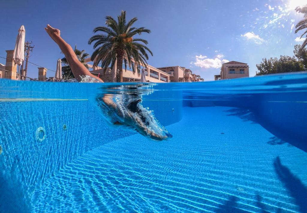 a person is swimming in a swimming pool at Isida Hotel Agia Marina in Agia Marina Nea Kydonias