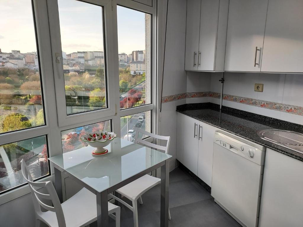 una cucina con tavolo, sedie e finestre di Apartamento Calzada Romana a Lugo