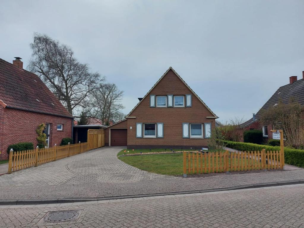 a house with a wooden fence in front of a driveway at Ferienwohnung/Norden/4Personen in Norden