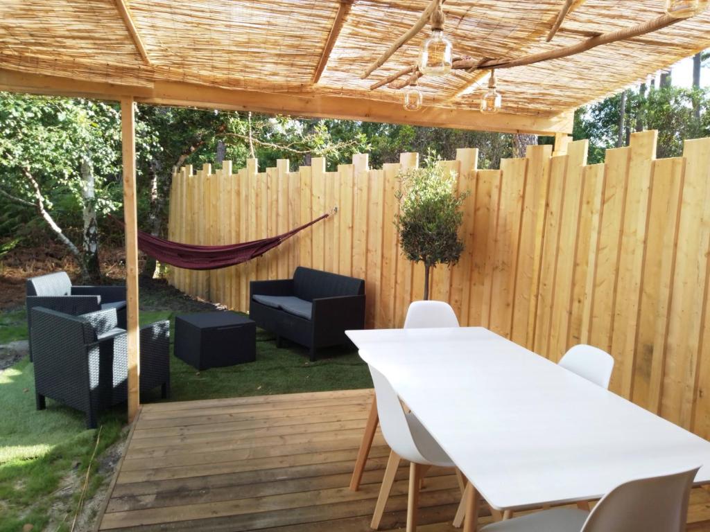 a patio with a white table and chairs and a fence at Studio dans les pins Lacanau in Lacanau