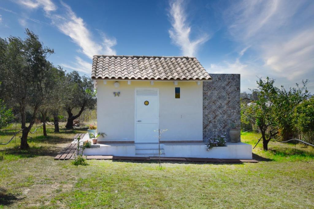 uma pequena casa branca com uma porta num campo em Casa vacanze FELICI IN 2 - Santa Maria del Focallo - Ispica em Santa Maria Del Focallo