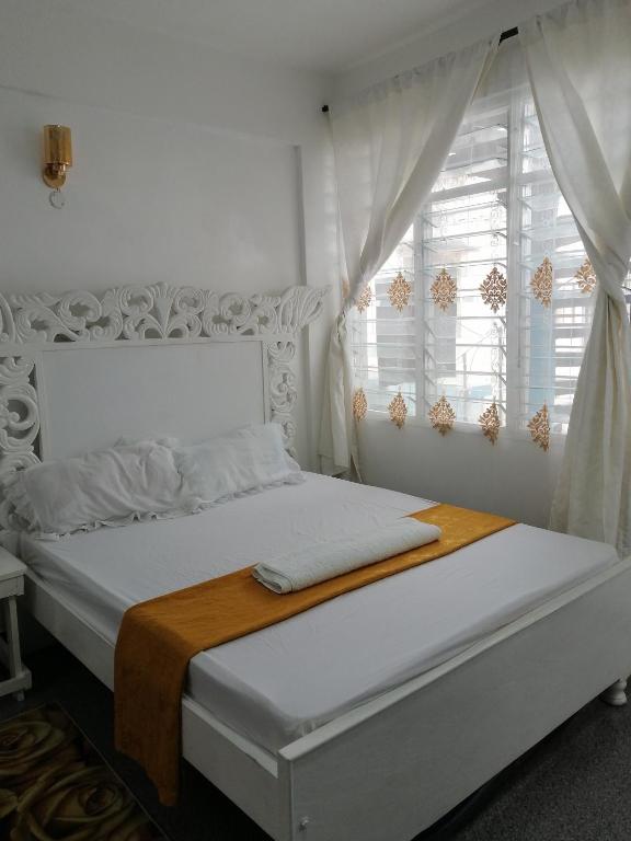 Dormitorio blanco con cama y ventana en Golden Nest, en Mombasa