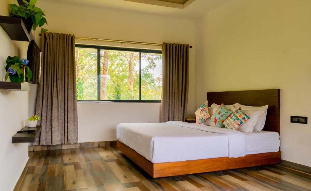 a bedroom with a bed and a large window at Mannoor Farms Mountain View Stays, Munnar in Munnar