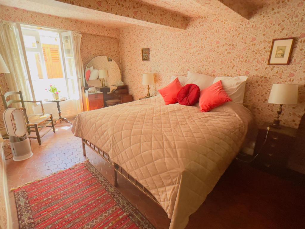 a bedroom with a large bed with red pillows at La Chambre Rose-Maison Searle à Tourtour in Tourtour