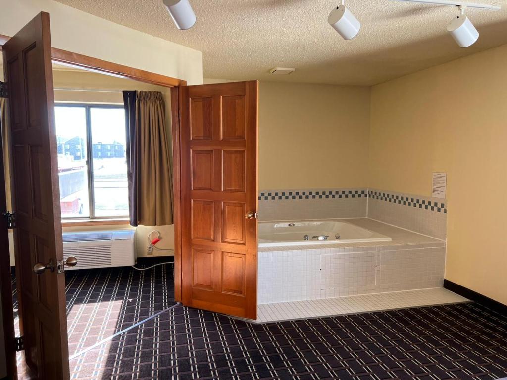 La grande salle de bains est pourvue d'une baignoire et d'une fenêtre. dans l'établissement Super 8 by Wyndham Watertown WI, à Watertown
