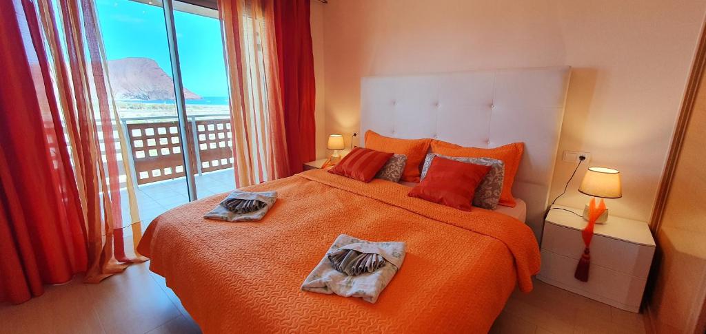 a bedroom with a large orange bed and a large window at Okeanos fantastic 2 bedrooms VR-PN in El Médano