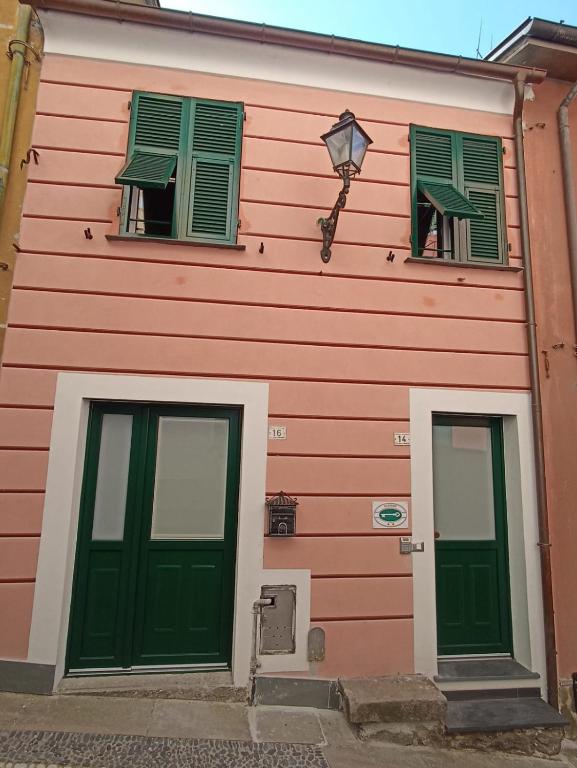 a pink building with green doors and windows at Elicriso Apartment Affittacamere in Borzonasca