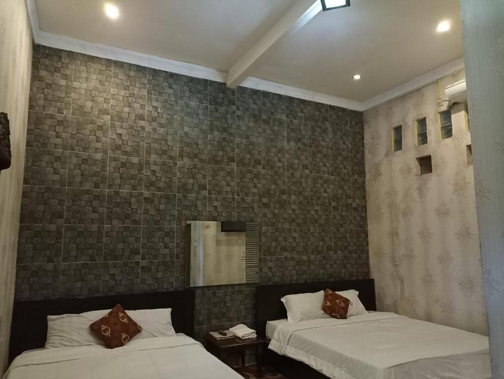 a bedroom with two beds and a mirror at Penginapan & Guest House Mbok Dhe Borobudur in Borobudur