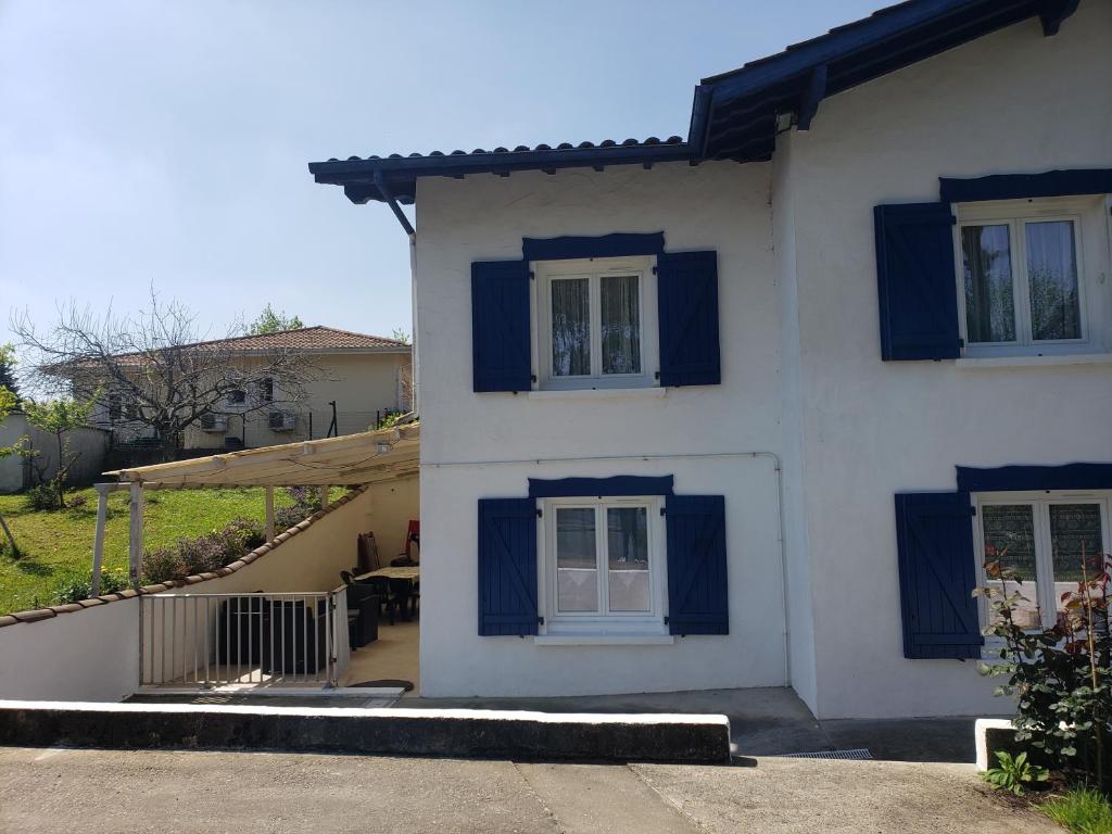 Una casa blanca con persianas azules. en Appartement T3 3 étoiles à 4 km de la plage, en Tarnos