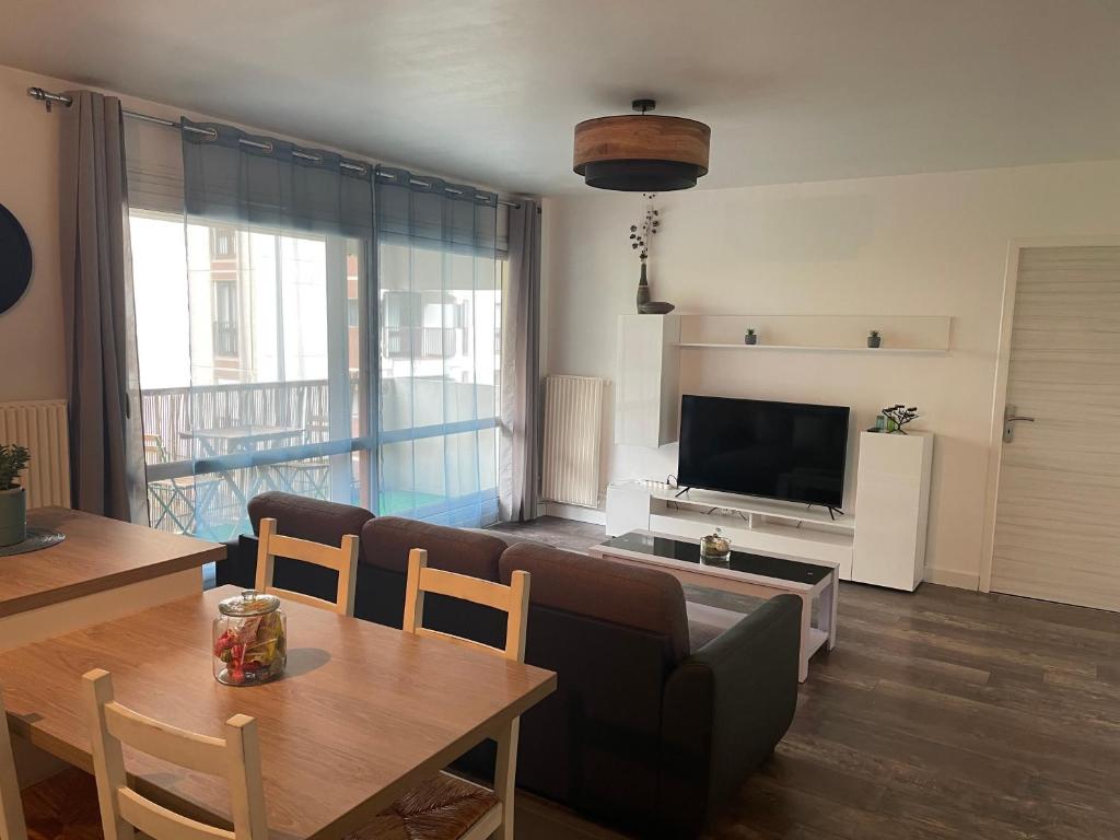 a living room with a table and a television at Bel appartement composé de deux chambres in Saint Etienne