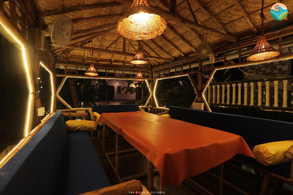 comedor con mesa, sillas y luces en Tropical Wave Hostel Morjim en Morjim