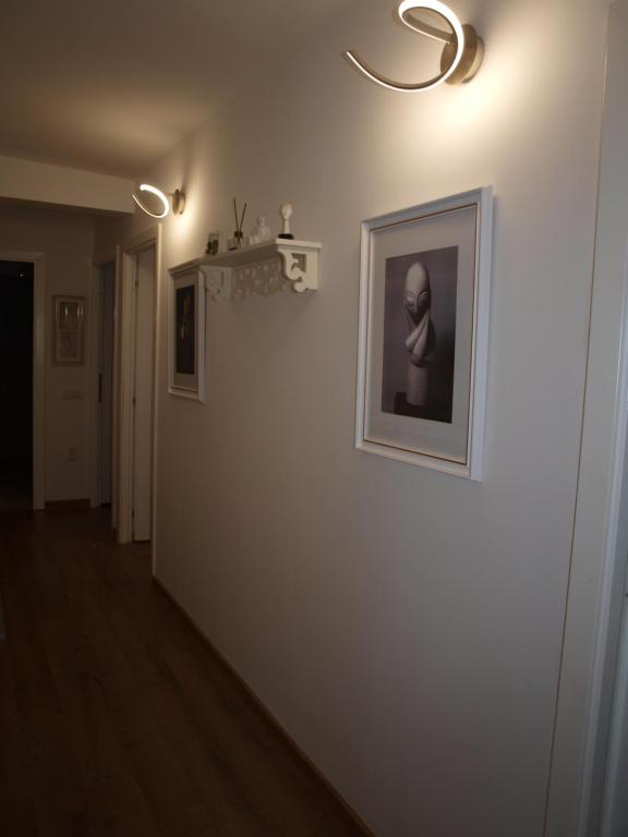 einen Flur mit einem Bild an einer weißen Wand in der Unterkunft Amavera Apartment in Târgu Jiu