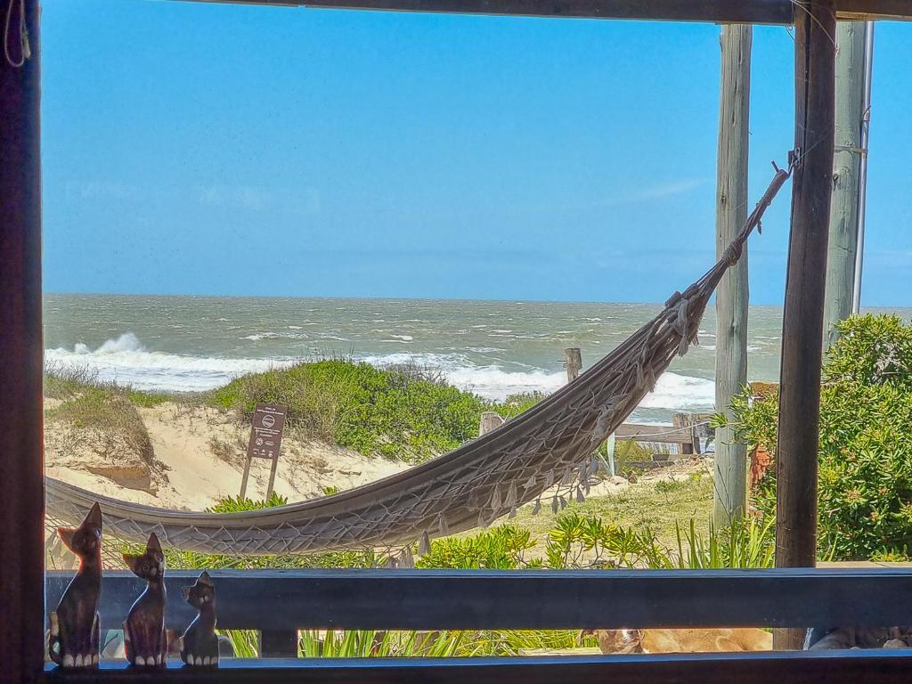 a hammock with a view of the ocean from a window at Cabañas Kundalini Punta del Diablo in Punta Del Diablo