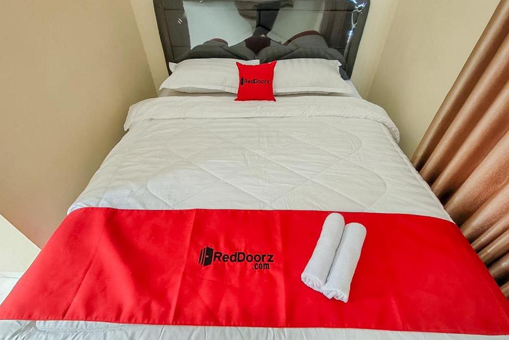 a red and white bed with white socks on it at RedDoorz near BNS Batu in Tlekung