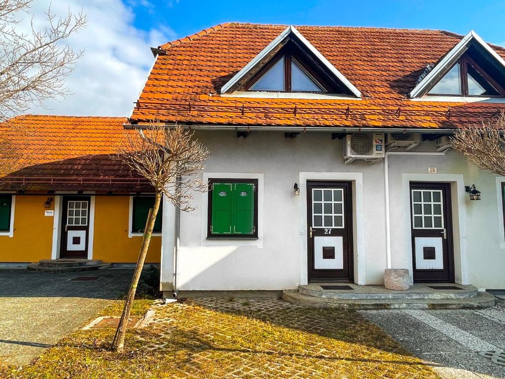 Biały dom z pomarańczowym dachem i zielonymi drzwiami w obiekcie Mad House Apartment 1, Terme Čatež w mieście Čatež ob Savi