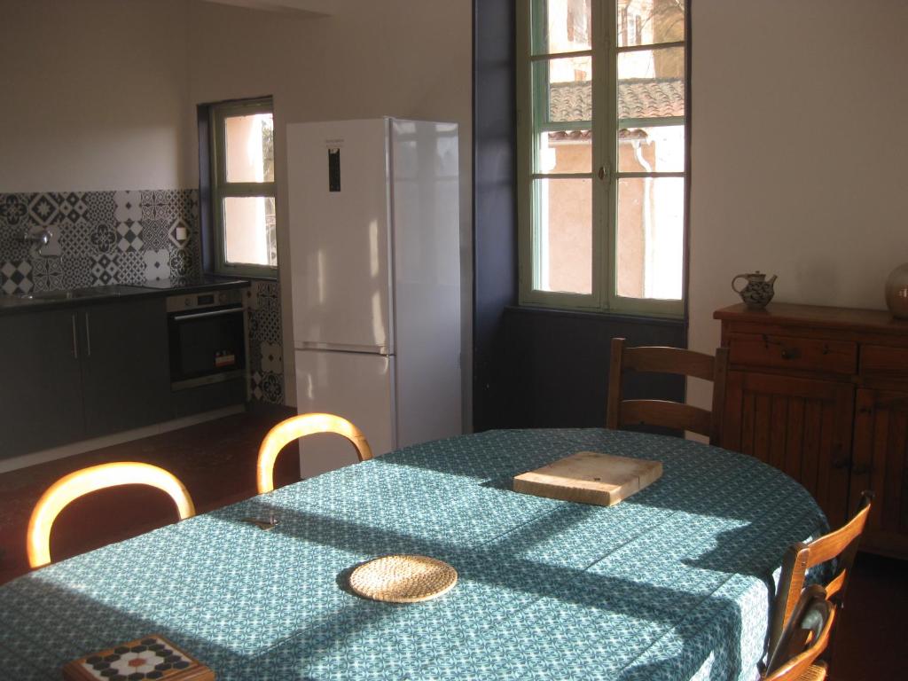 uma cozinha com uma mesa com uma toalha de mesa azul e um frigorífico em Les deux pentes em Sausses