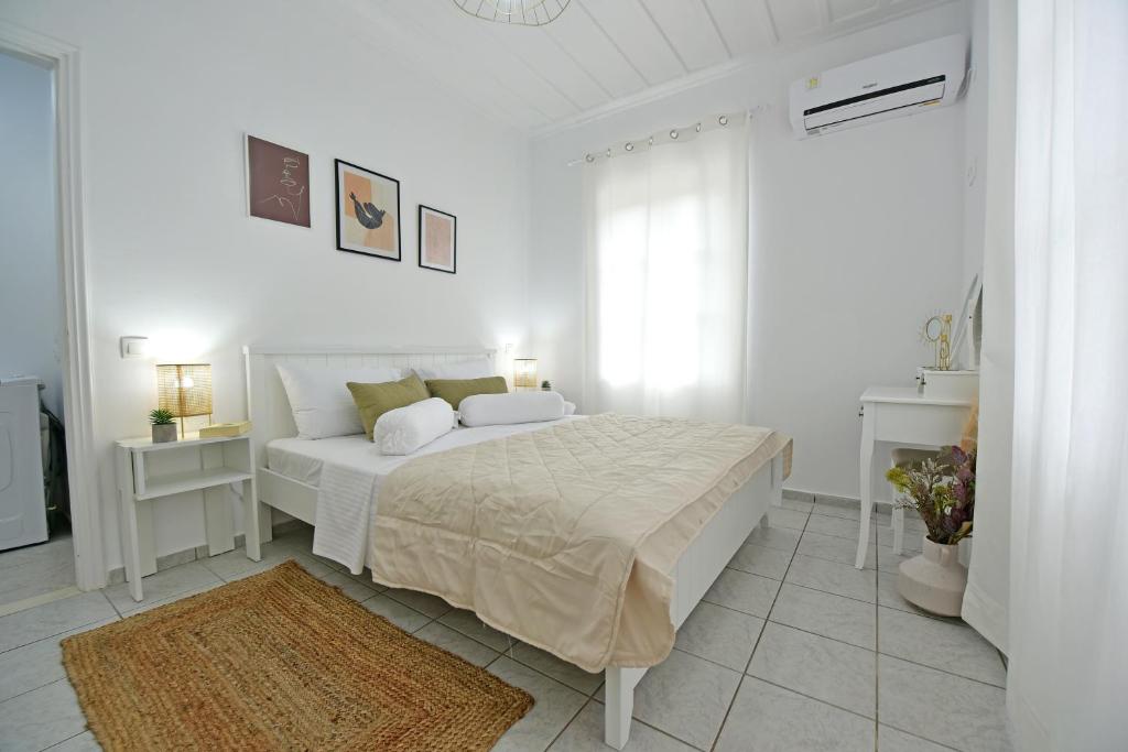 a white bedroom with a white bed and a window at Olivo luxury apartment in Hydra