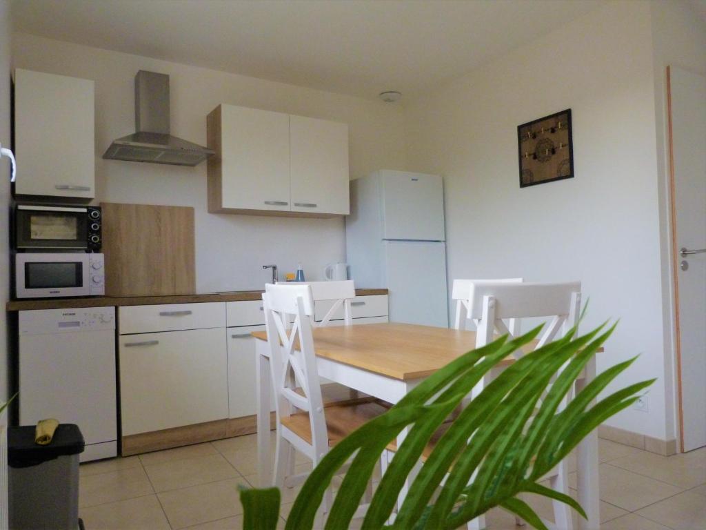 cocina con mesa de madera y armarios blancos en Gîte de L'Epicière, en LʼÉpaux