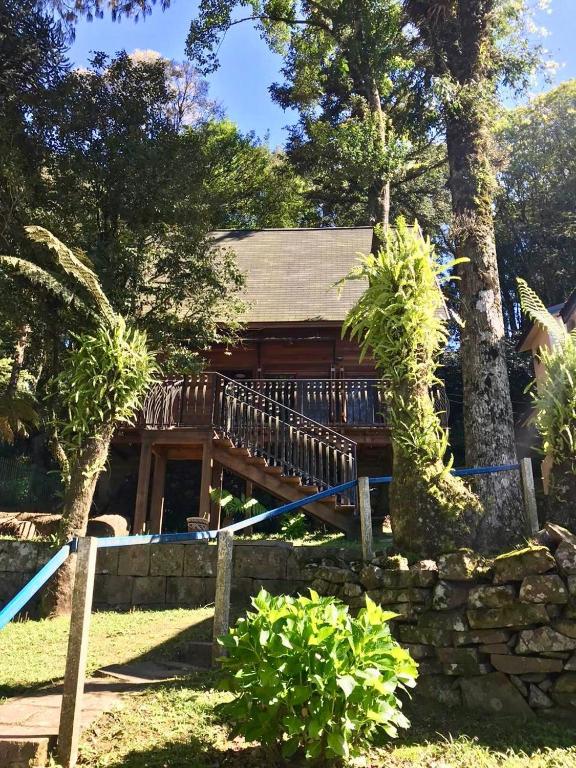a log cabin with a fence and trees at Chalé Romântico - Gramado in Gramado