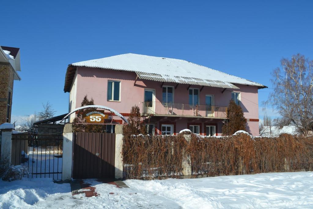 a pink house with a fence in the snow at Hostel Ask in Karakol