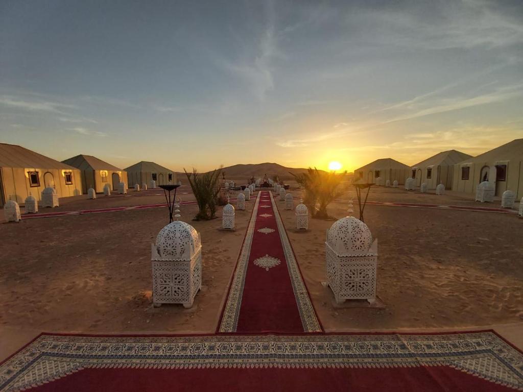 a road in the middle of a desert with a sunset at Luxury Desert Camp Amanar in Merzouga