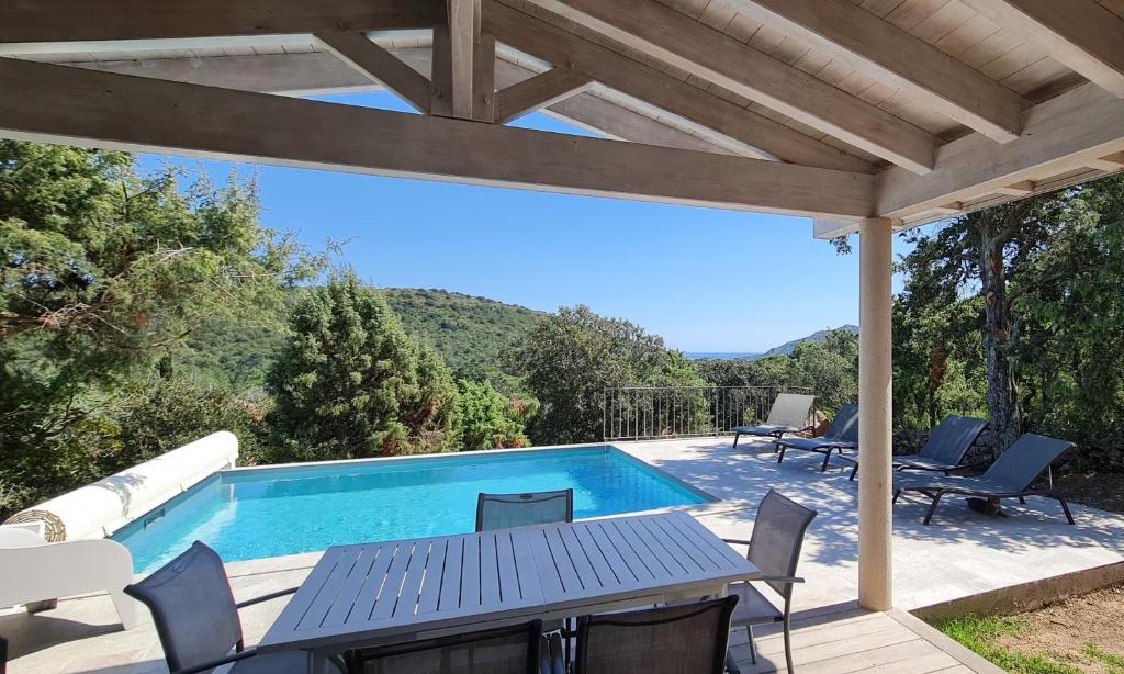 a patio with a table and chairs and a swimming pool at Villa Giulia in Porto-Vecchio