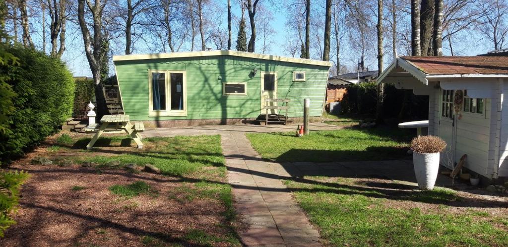 a green tiny house in the middle of a yard at Chalet op mooie rustige plek in Enschede