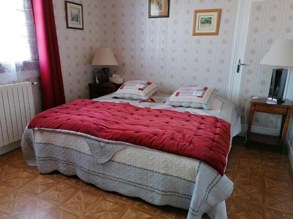 a bedroom with a large bed with a red blanket at Les Galets in Tracy-sur-Mer