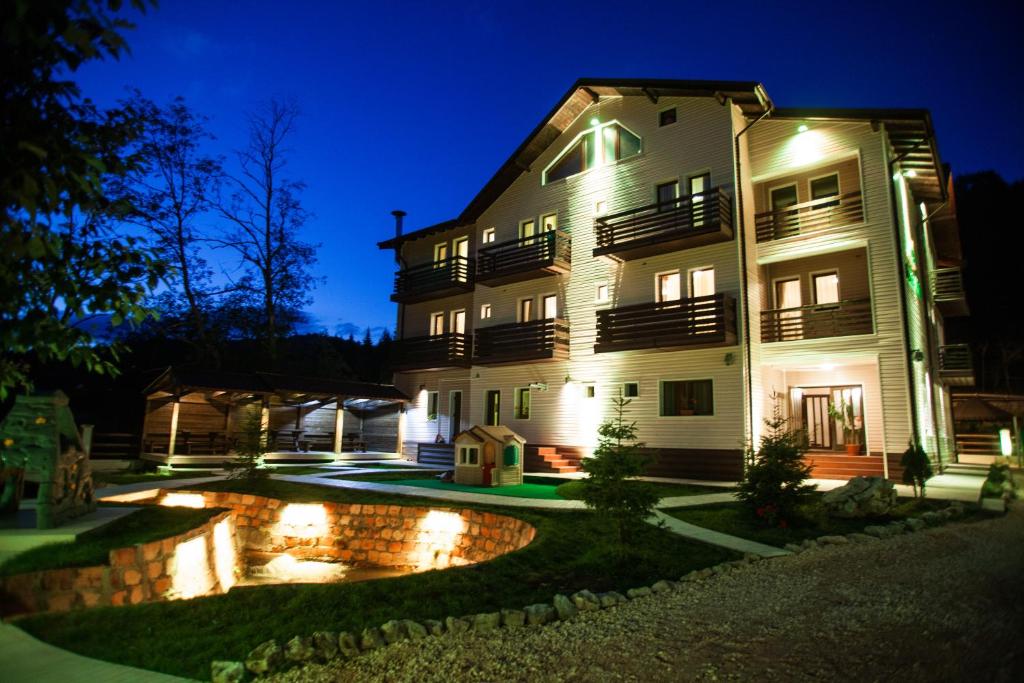 um edifício com um lago em frente à noite em Hotel Draga Maria em Predeal