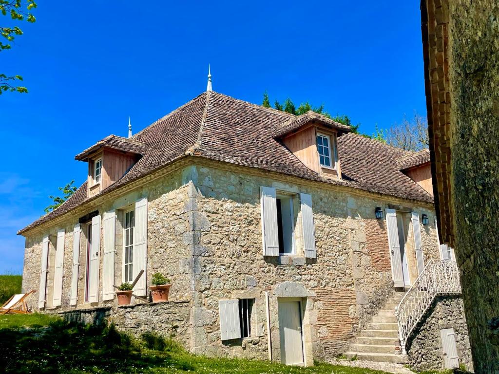 an old stone house with white shuttered windows and stairs at La Vignerie in Boisse