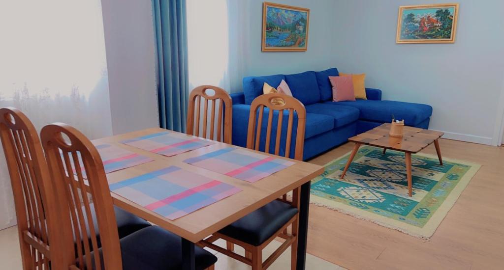 a living room with a table and a blue couch at Chestnut Yard Villa in Tirana