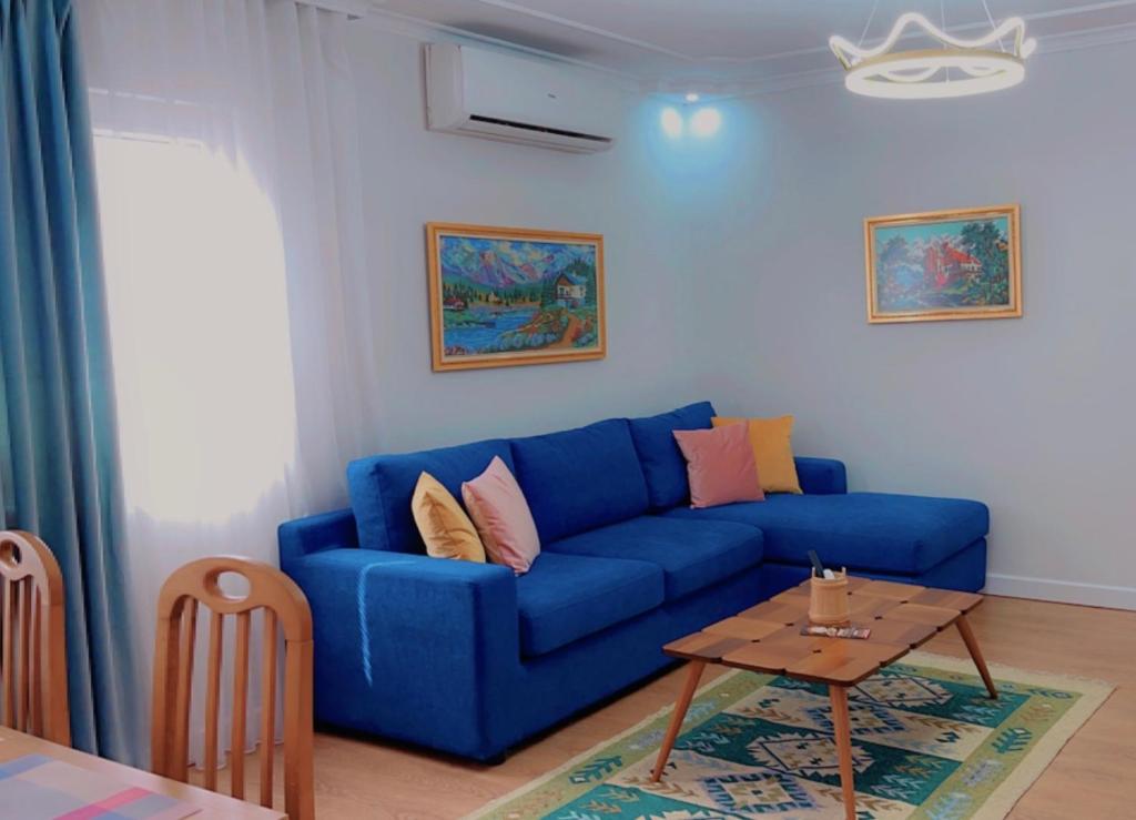 ein blaues Sofa im Wohnzimmer mit einem Tisch in der Unterkunft Chestnut Yard Villa in Tirana