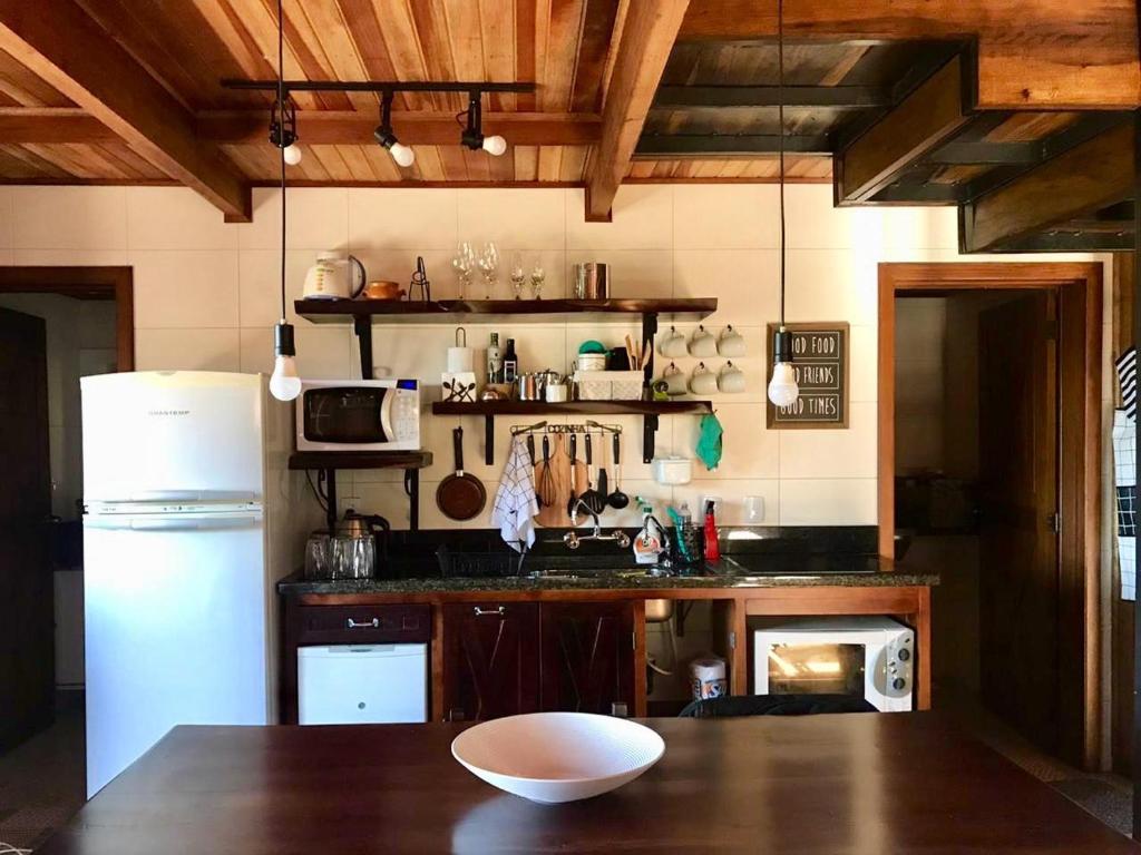 cocina con nevera blanca y mesa de madera en Chalé Romântico - Gramado en Gramado